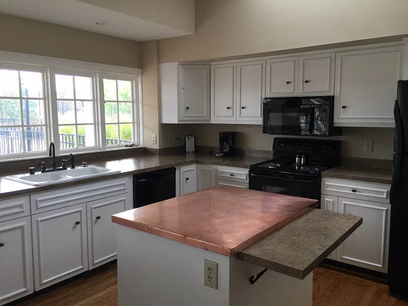 The clubhouse kitchen with a central island, white cabinetry and full-size appliances