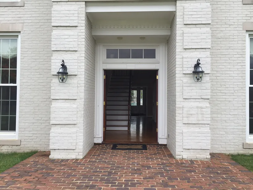 The rear entrance of the clubhouse, with painted brick columns, carriage lanterns and a brick patio