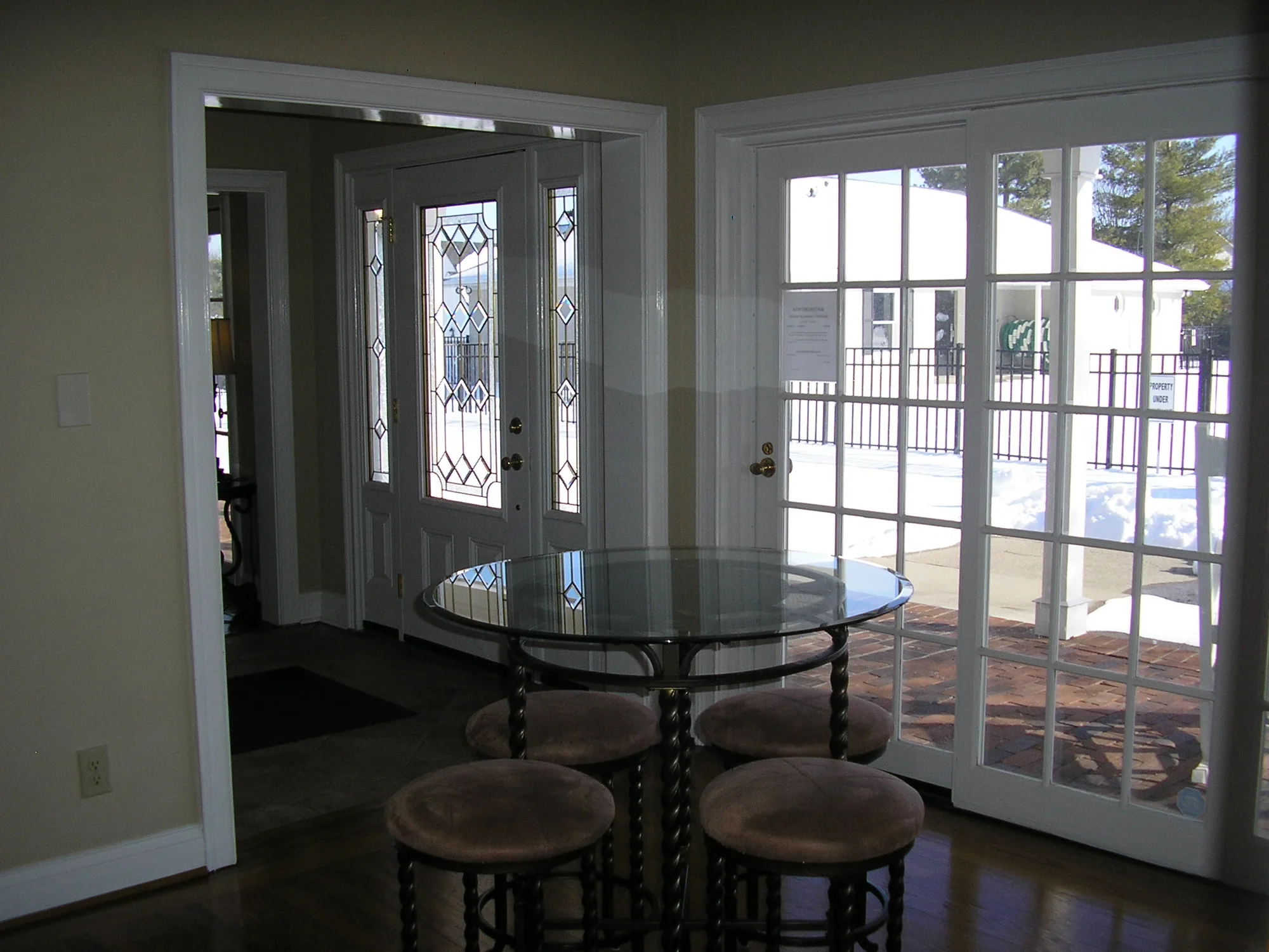 The entry room with a glass-topped table, stools and doors to the pool deck