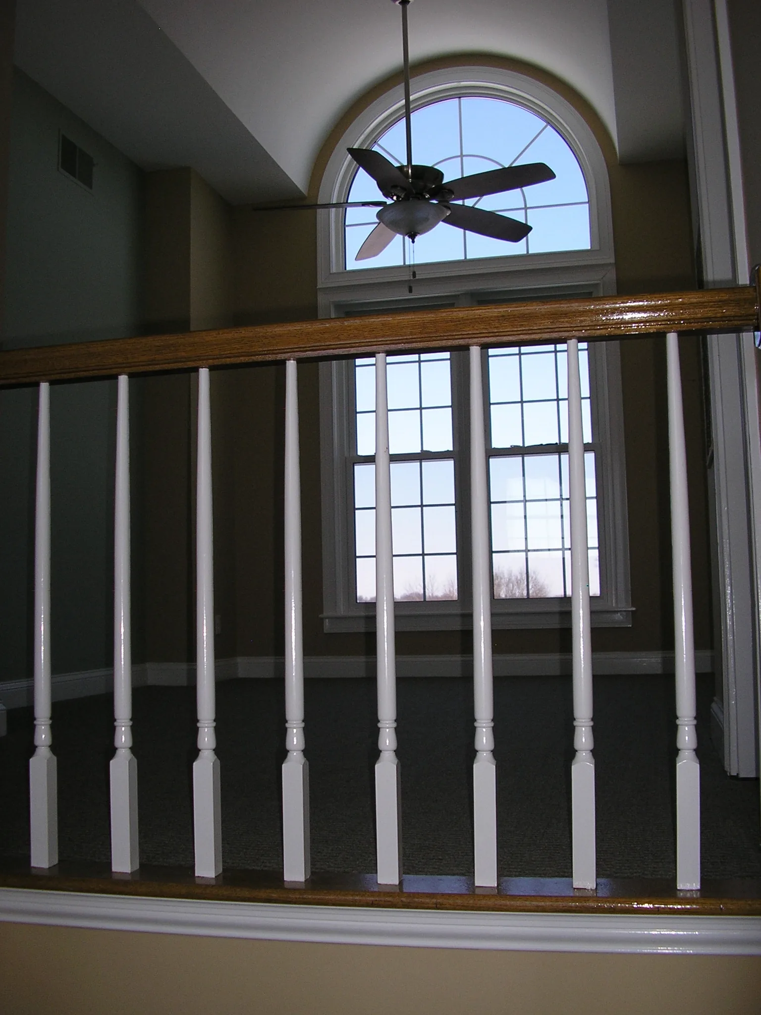 The stair balustrade and arched window above the entry