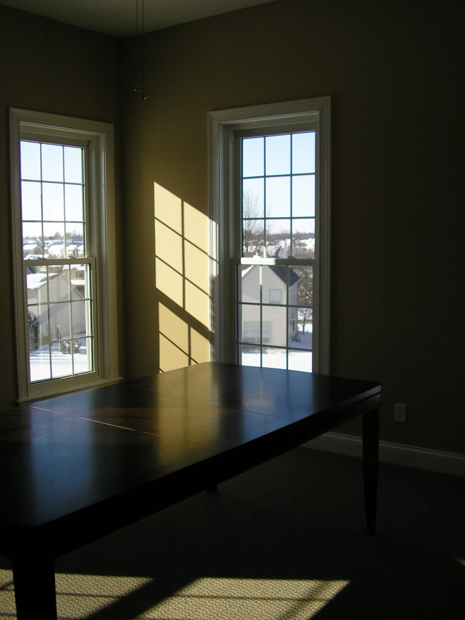 A room with draped windows and hardwood flooring